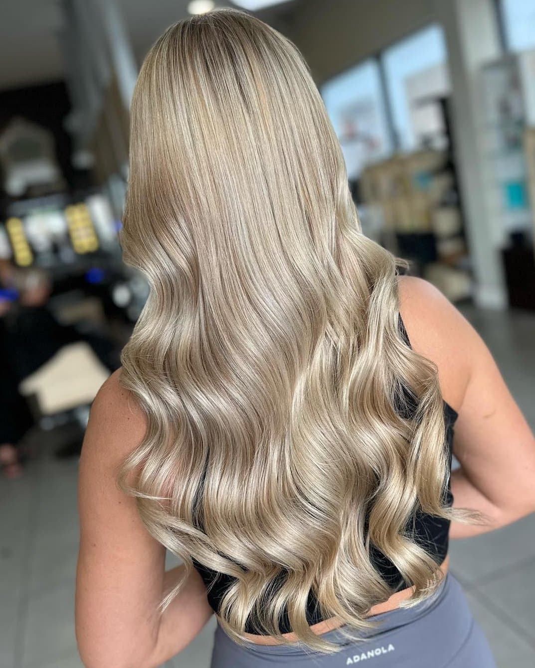 A picture of the back of a womans head showing long blonde curly hair.